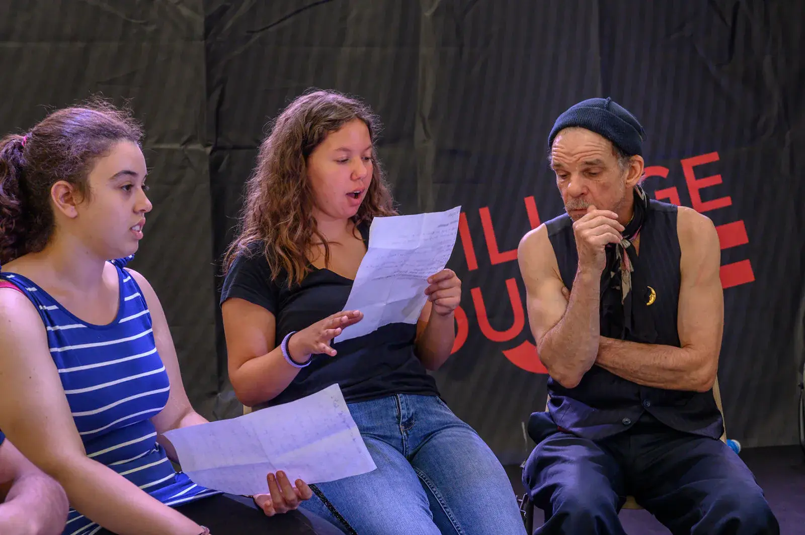 Trois jeunes lisent leurs textes aux côtés d’un comédien en répétition.