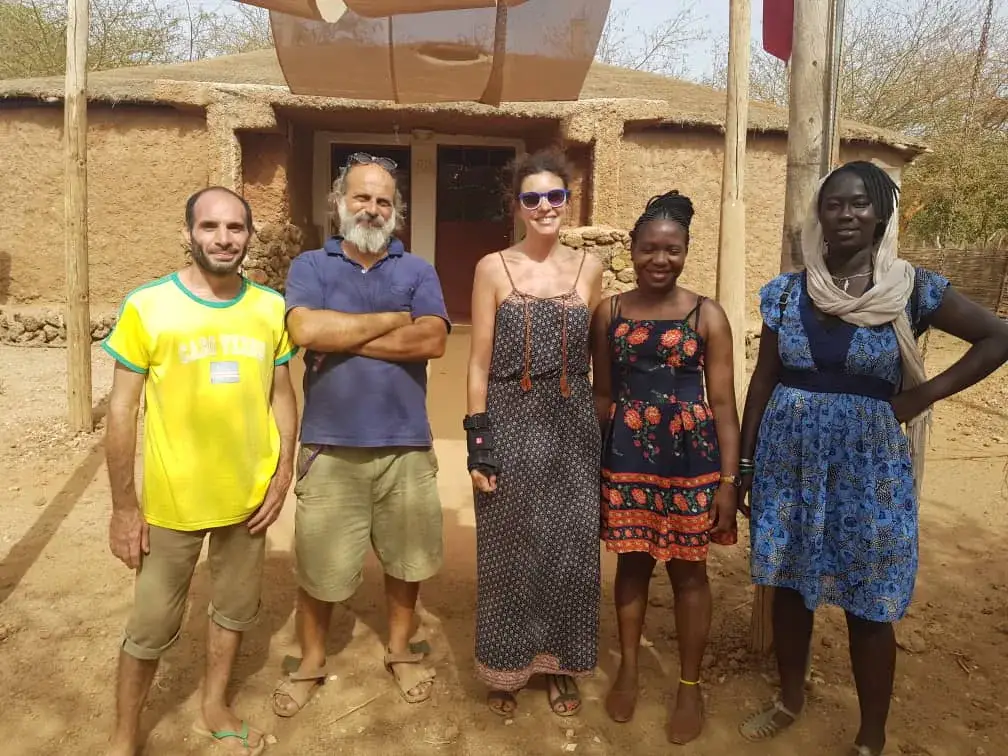 Cinq personnes posent devant un bâtiment en banco lors d’une mission au Sénégal.