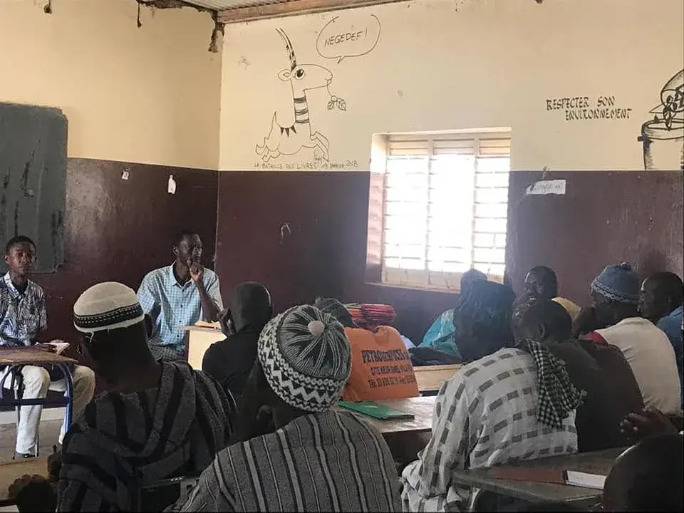 Une réunion de présentation dans une salle de classe, face à un public attentif.