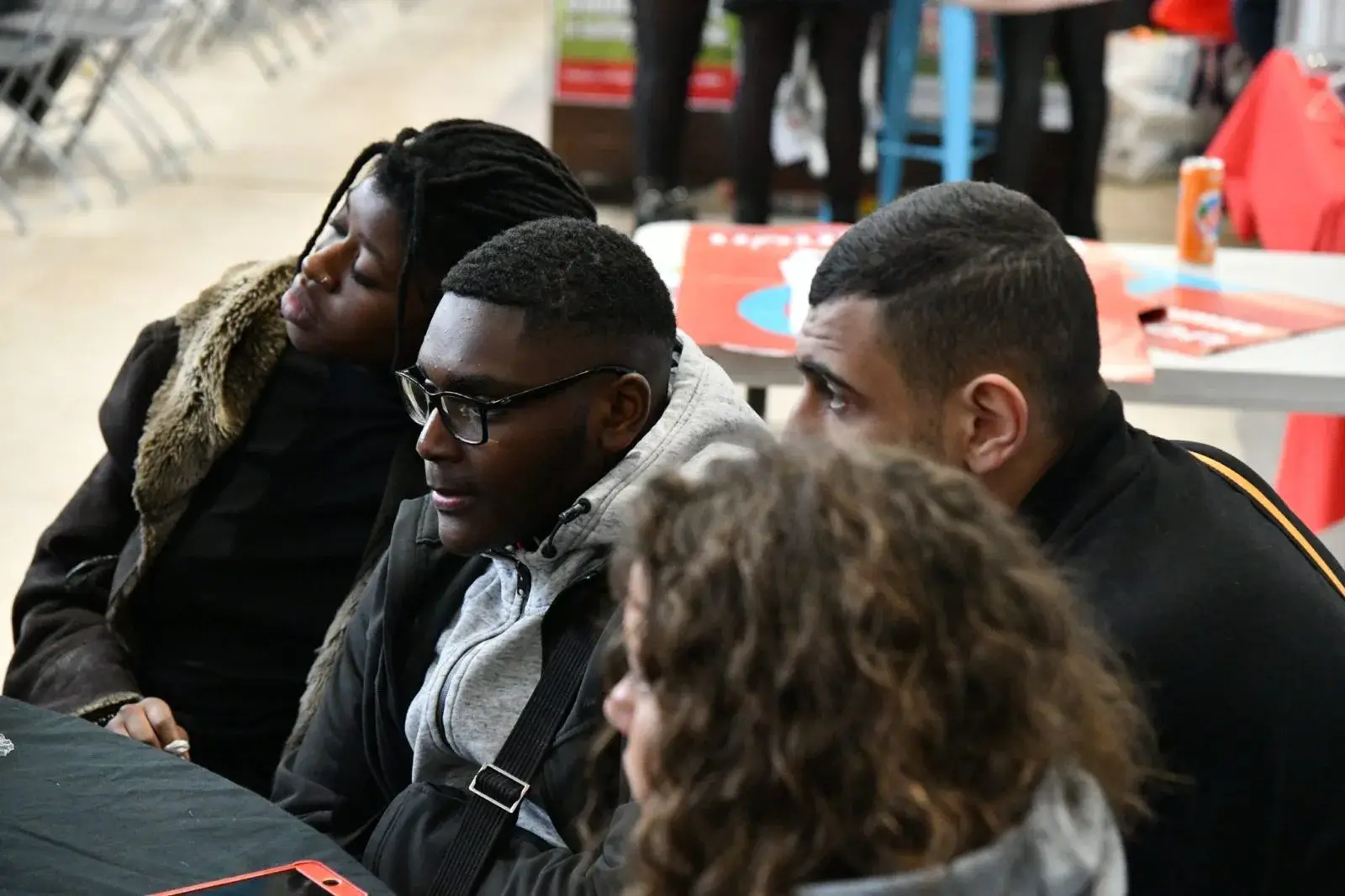 Trois jeunes participent à une discussion autour d’une table.