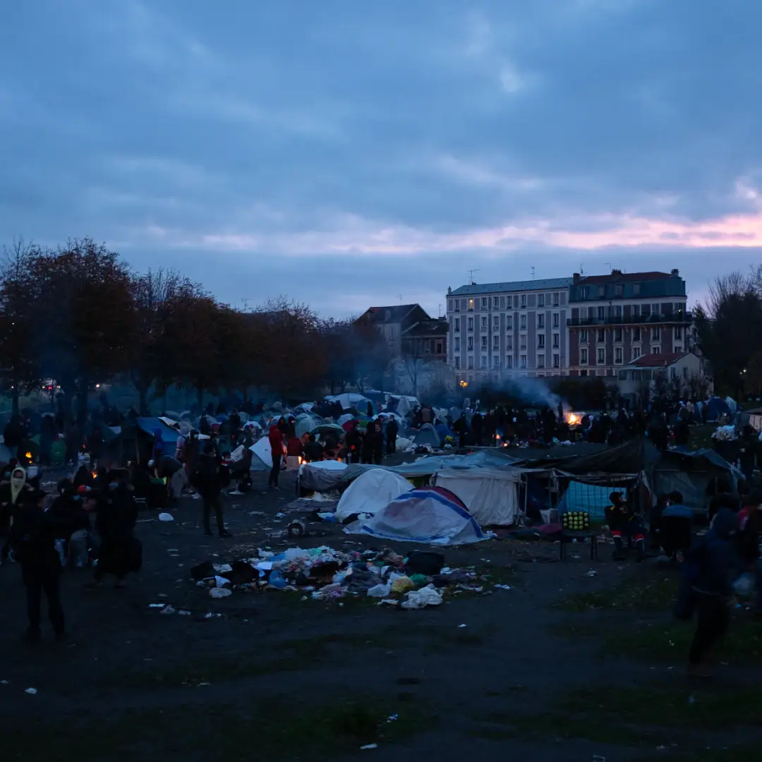 Campement de tentes et de personnes exilées au crépuscule à Saint-Denis