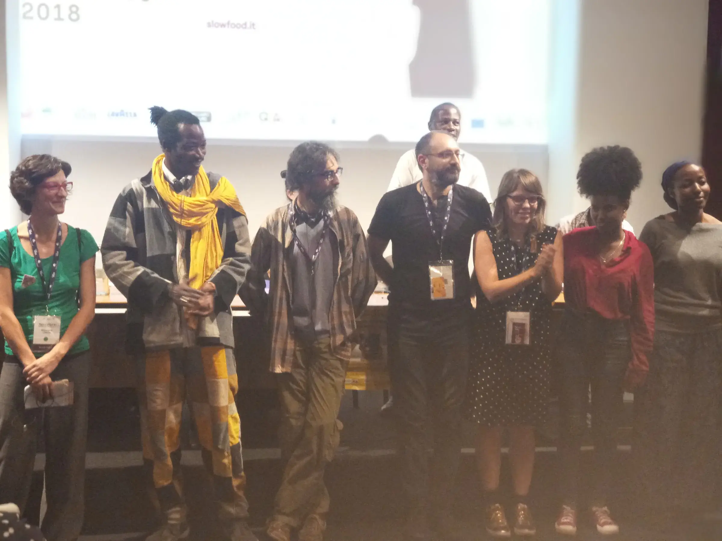 Un groupe de participants se tient sur une scène lors d’une présentation.