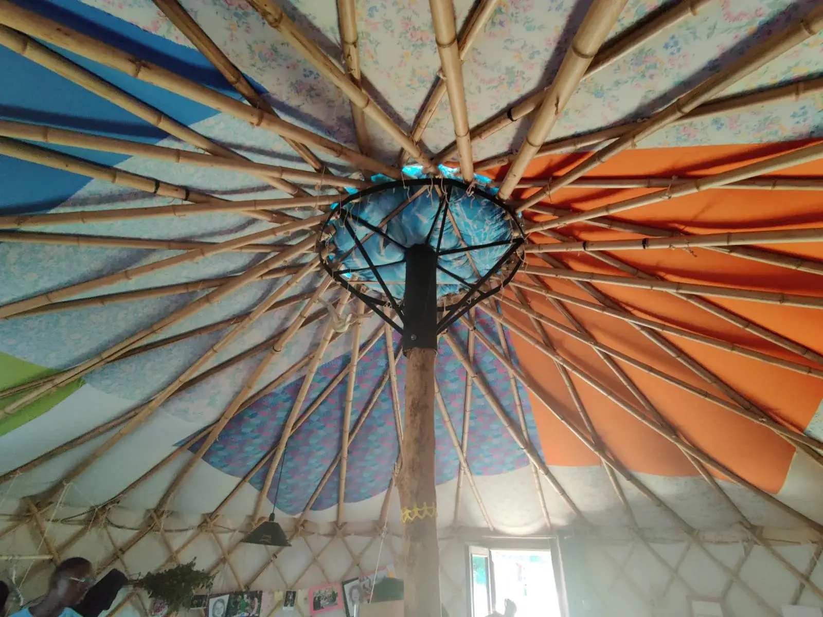 L’intérieur d’une yourte et sa charpente en bois vue depuis le sol.