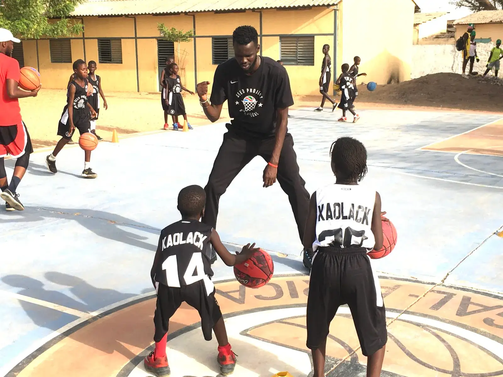 Entraînement de basketball : un coach et deux jeunes joueurs dribblant sur un terrain extérieur