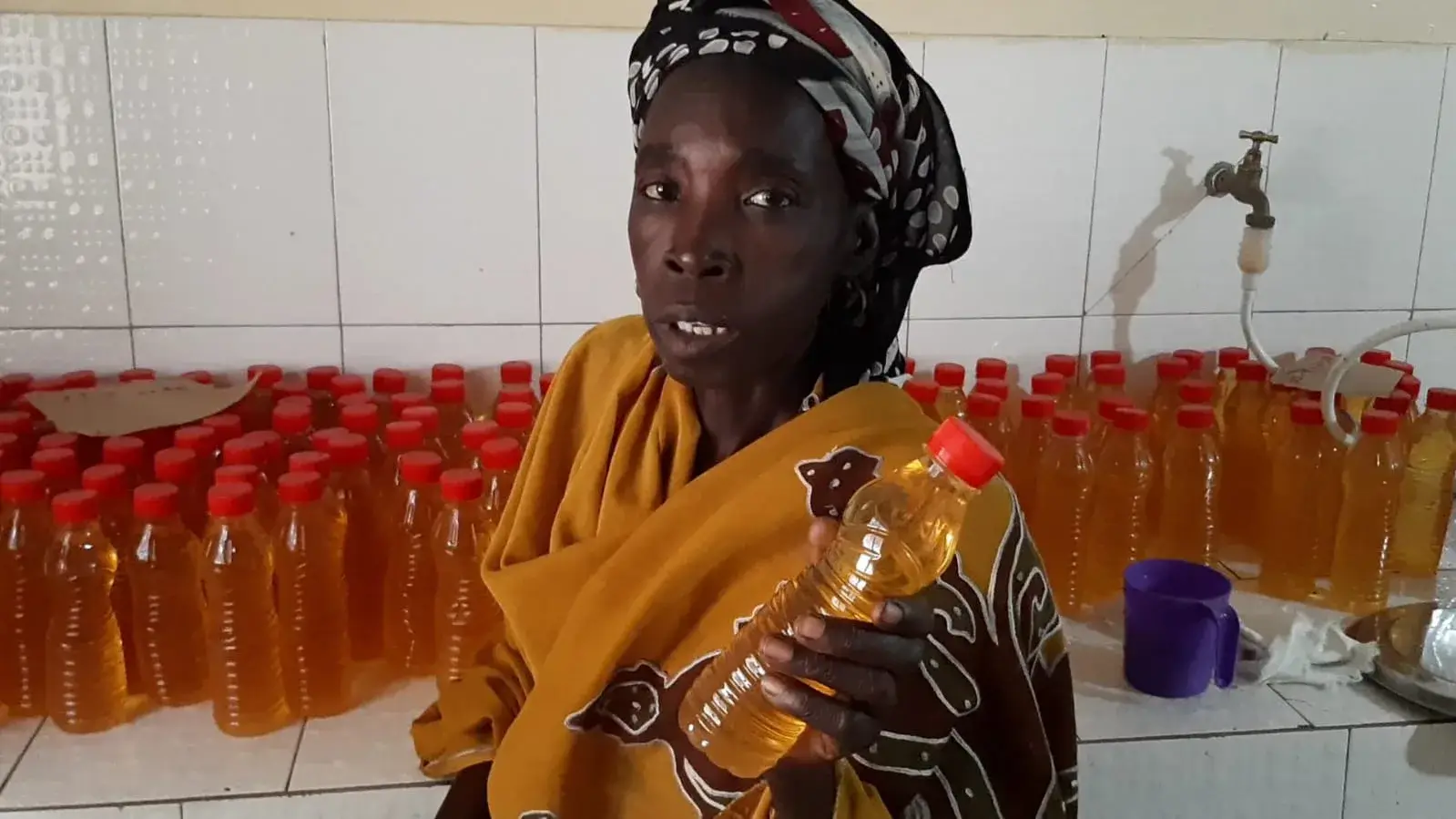 Une productrice présente une bouteille de jus de pomme de cajou.