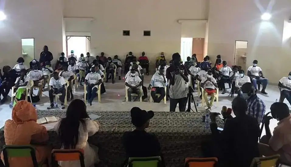 Public assis face à une table ronde lors d’un forum dans une grande salle