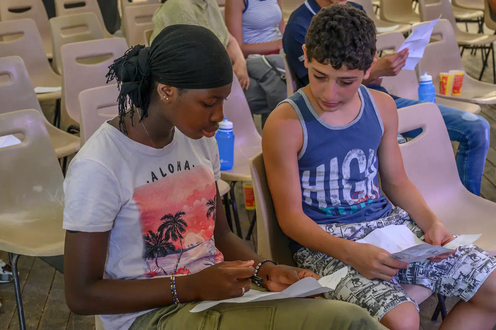 Deux adolescents assis dans un auditorium lisent leur script.