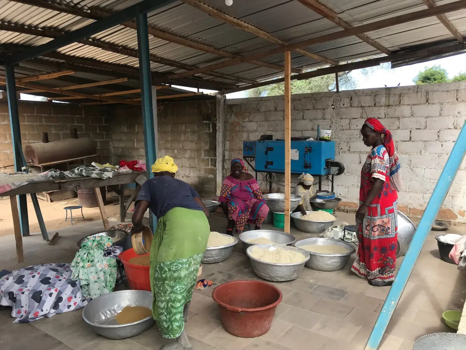 Des femmes transforment les noix de cajou dans un atelier, entre bassines et machine
