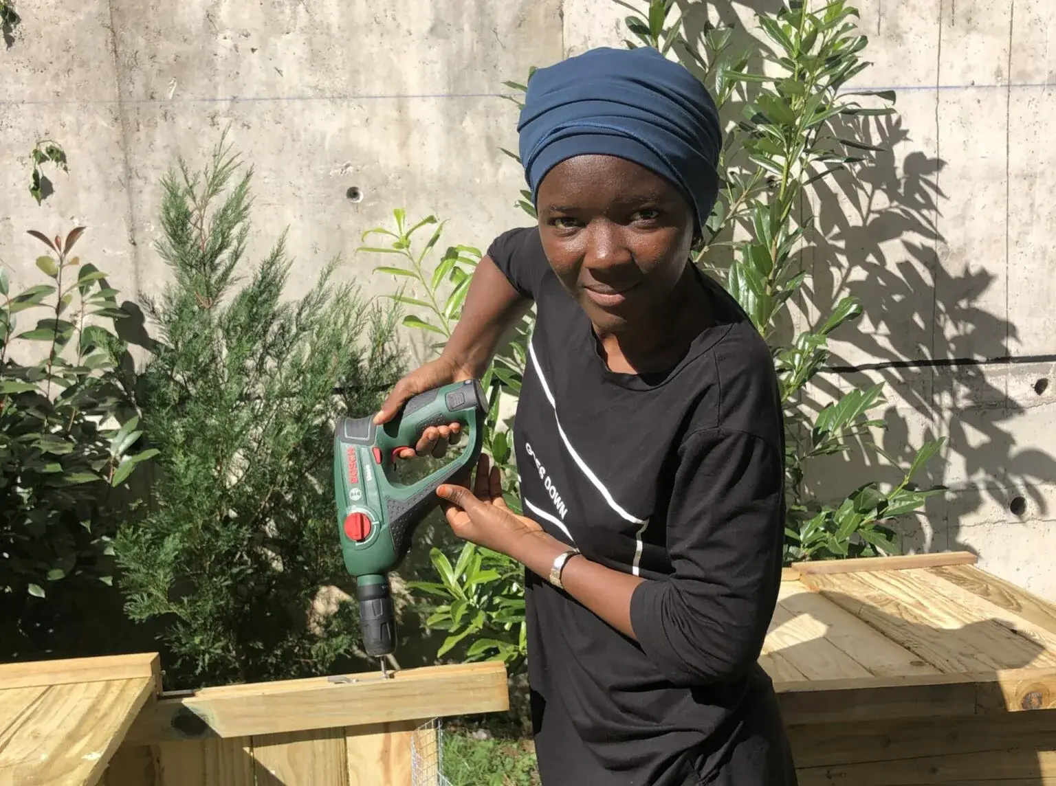 Maimouna avec une perceuse sur le chantier du jardin partagé