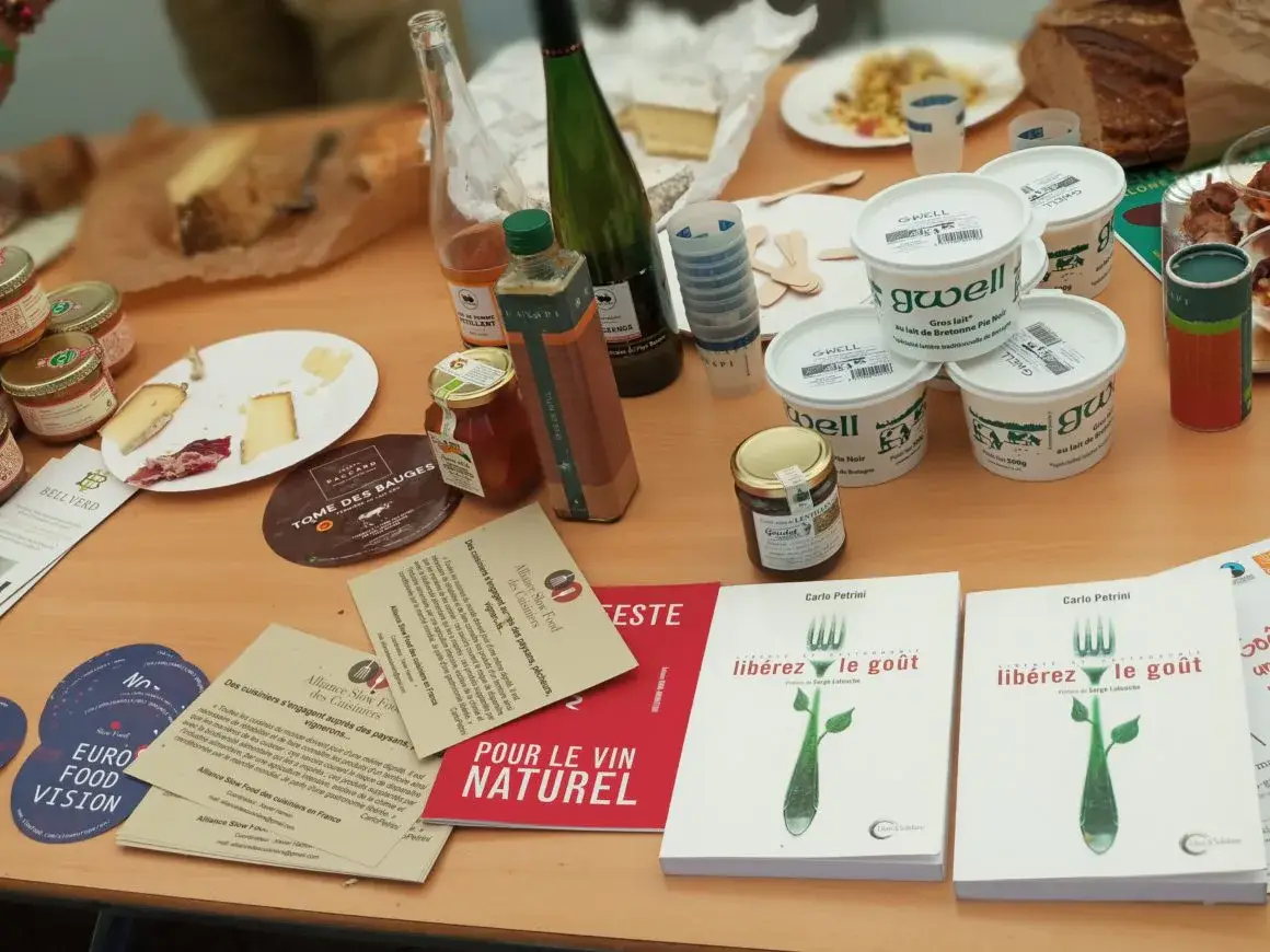 Une table couverte de produits locaux, de livres et de documents sur l’alimentation.