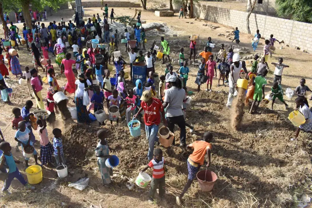Une grande activité collective réunit enfants et adultes dans un village.