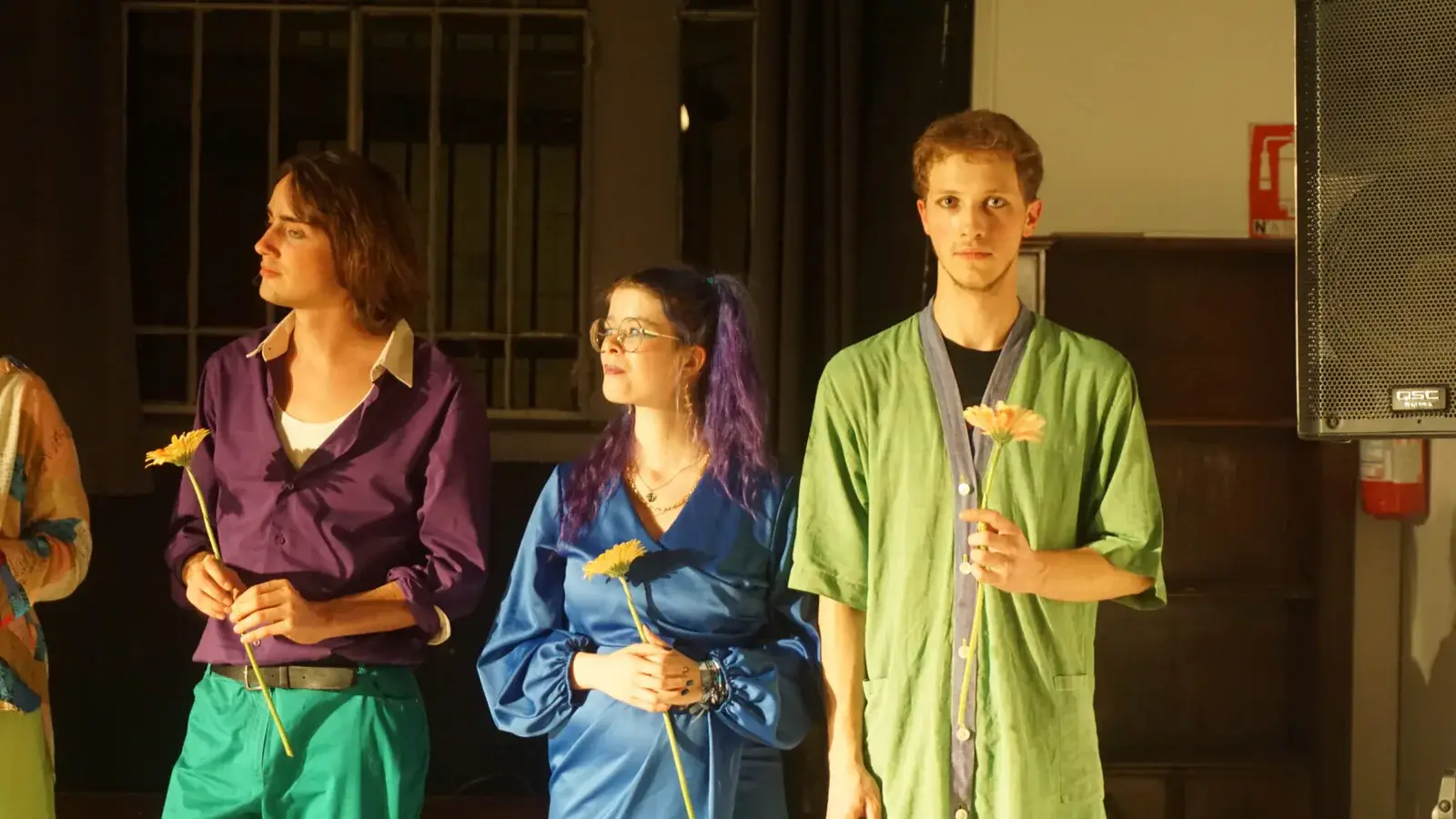 Trois comédiens en costumes, une fleur à la main, sur scène