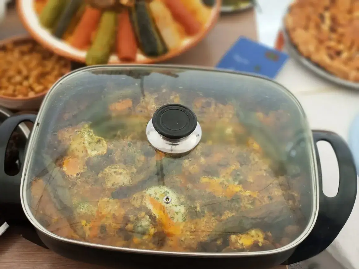 Un grand faitout de légumes et de poisson entouré de plats.