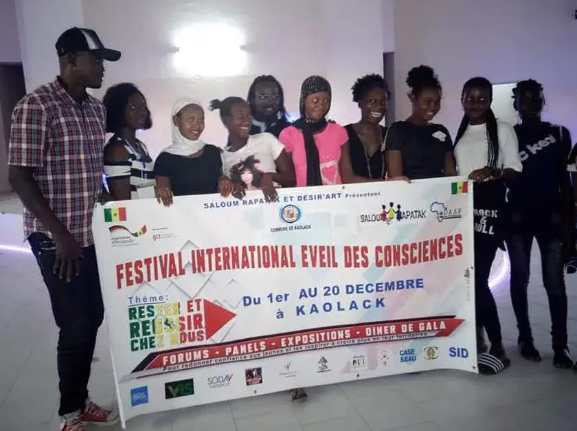 Groupe de jeunes posant derrière une banderole du Festival international Éveil des consciences