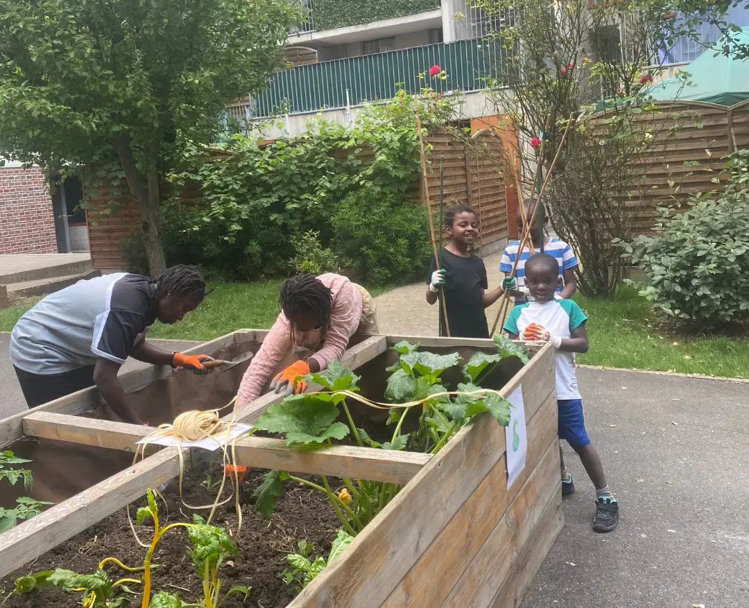 Enfants et adultes autour des bacs de culture du jardin