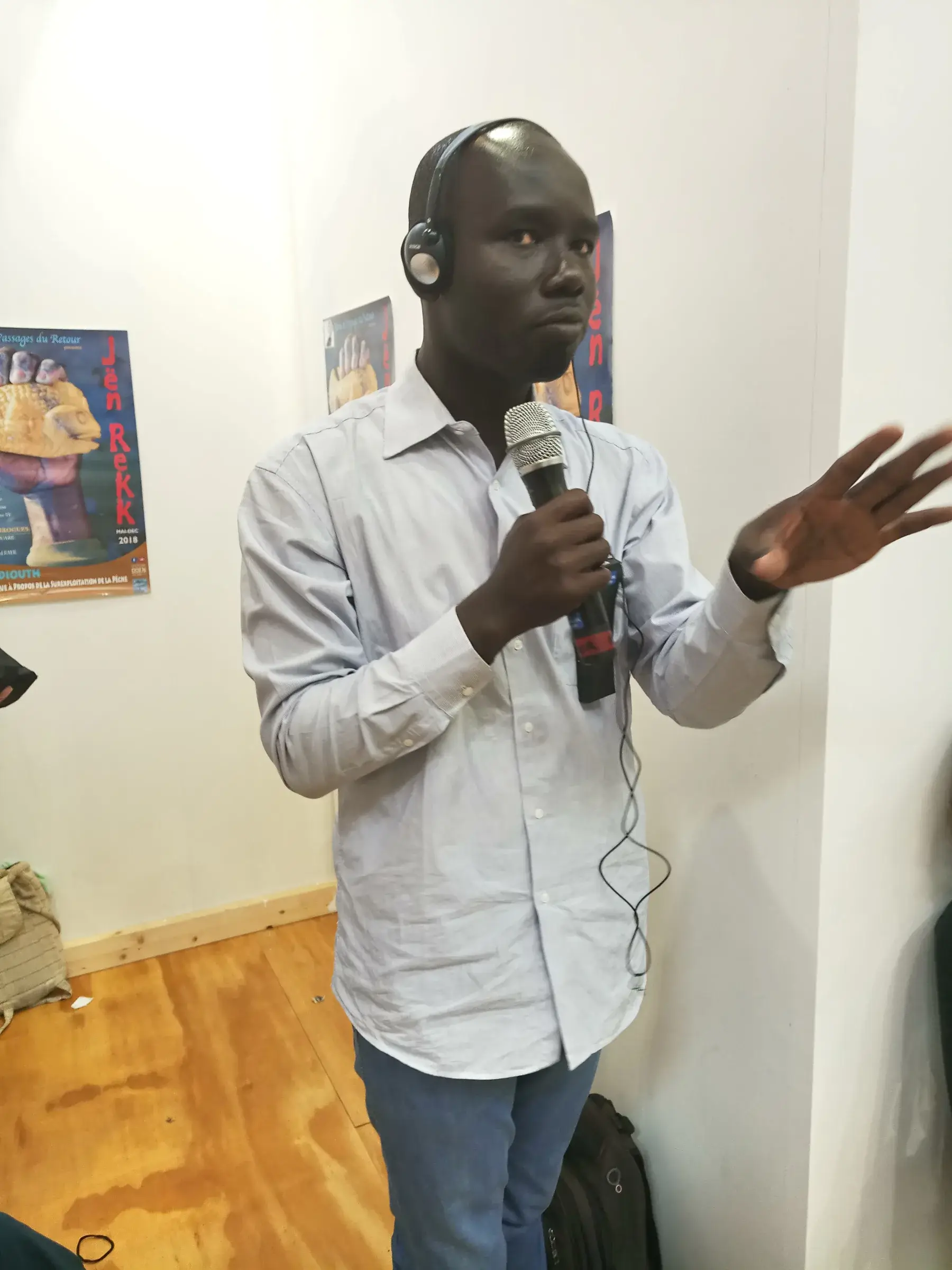 Un homme parle dans un micro devant un tableau, dans une salle.