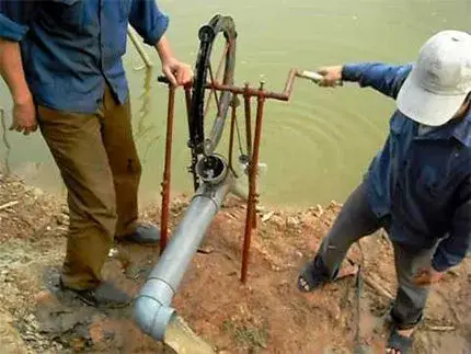 Deux personnes actionnent une pompe à vélo près d’un point d’eau.