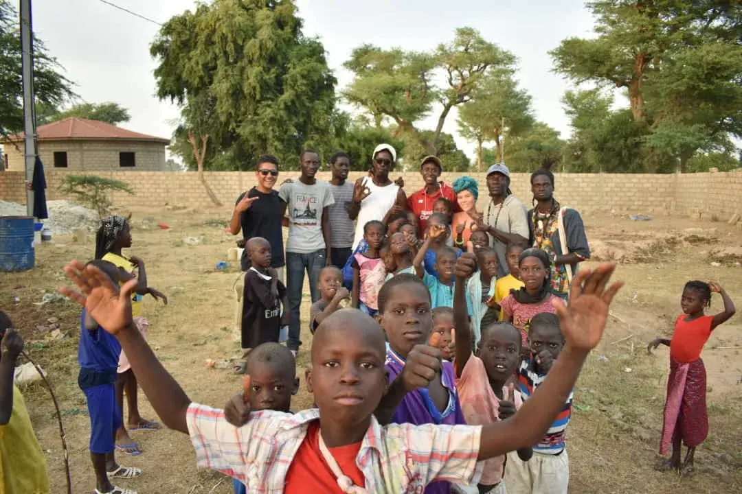 Des enfants et des adultes lèvent les mains lors d’une rencontre.
