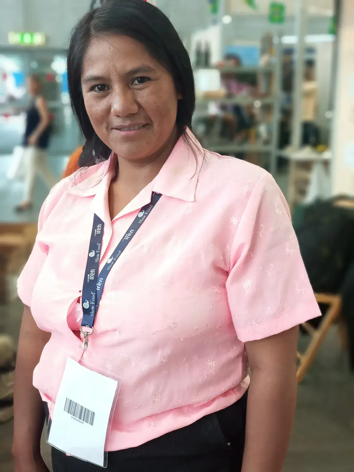 Portrait d’une exposante en chemise rose, badge Terra Madre autour du cou.