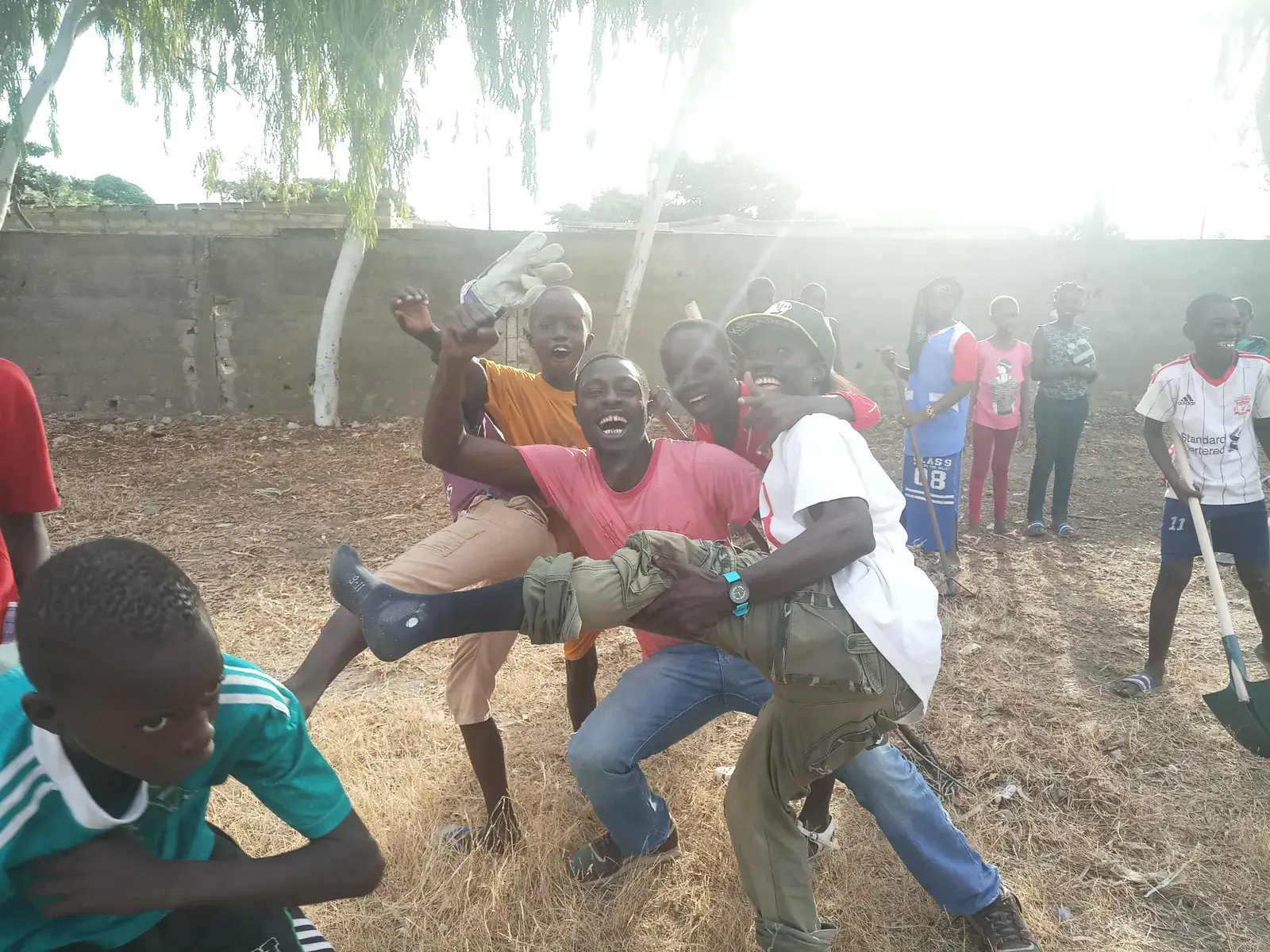 Des enfants jouent et posent dans une cour sablée.