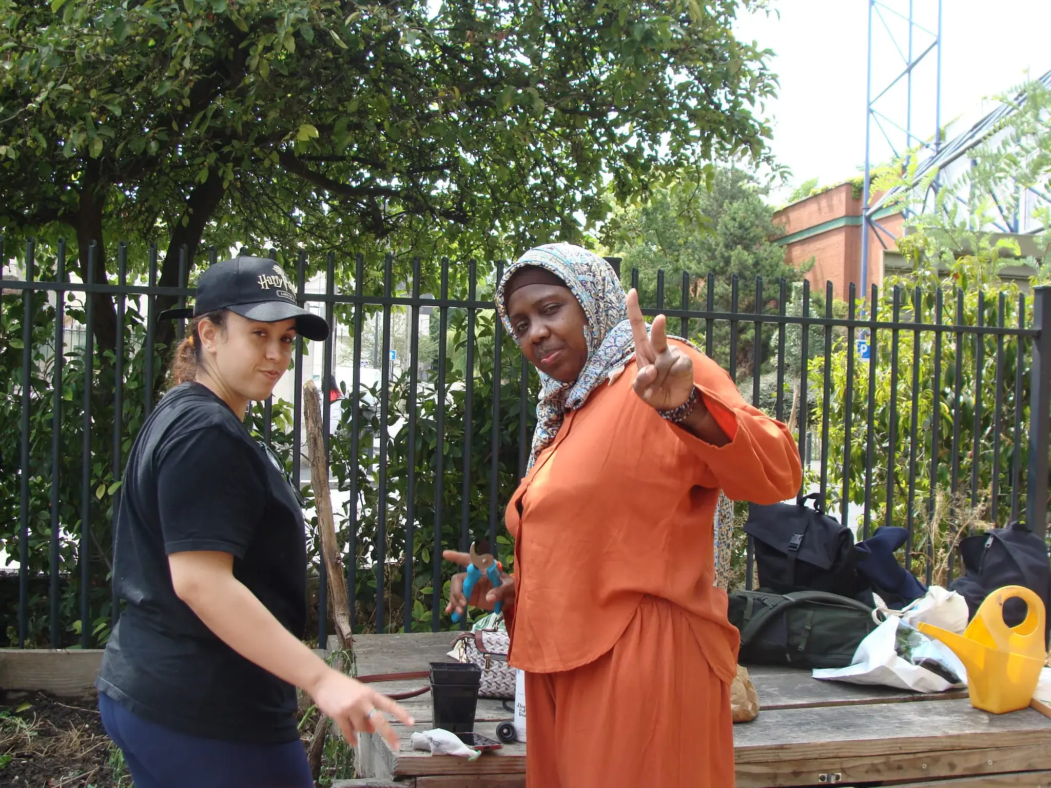 Deux femmes discutent près d’une table de pique-nique, l’une porte une tunique orange.