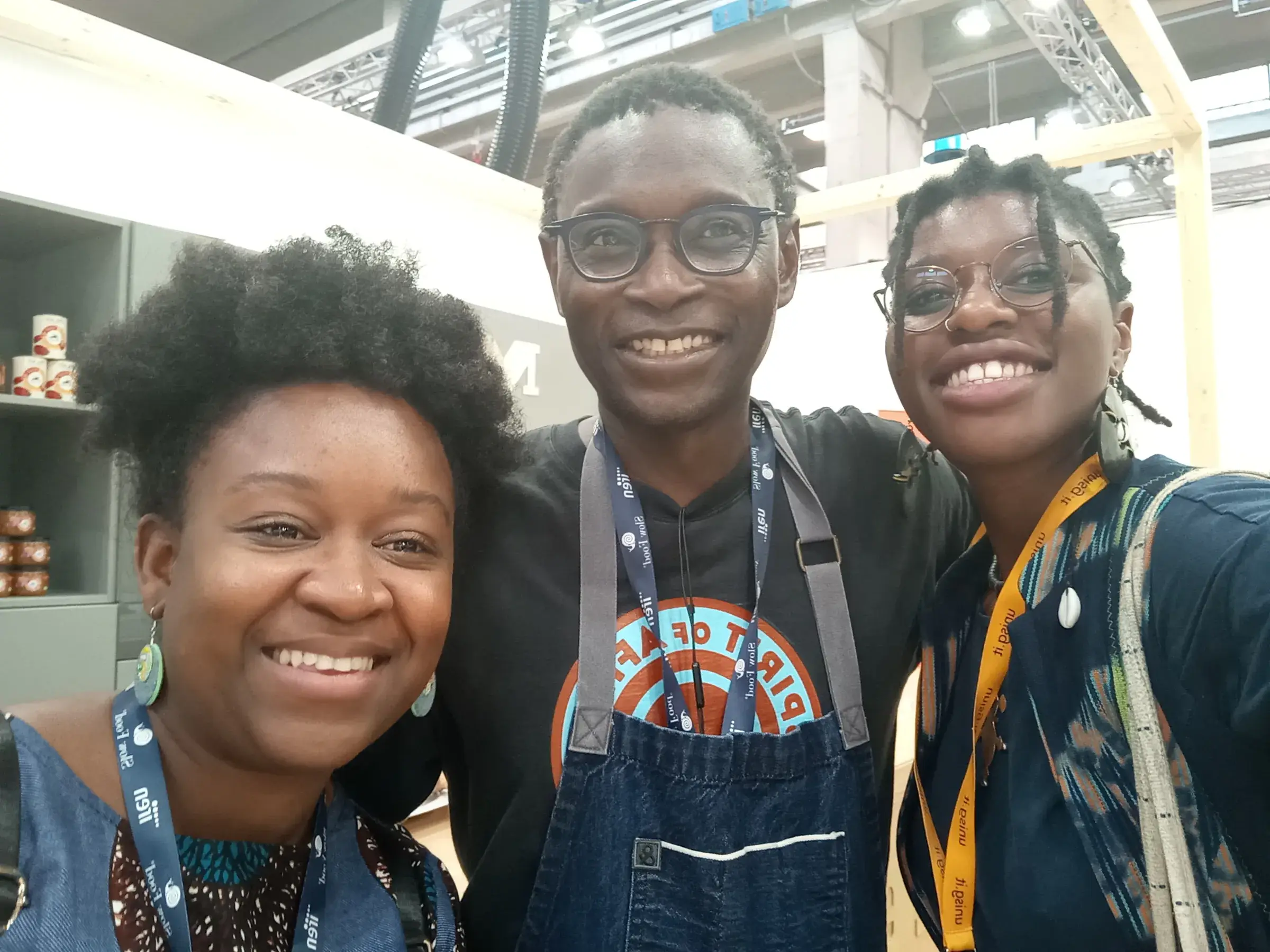 Trois jeunes gens souriants, deux portant un tablier de cuisine.