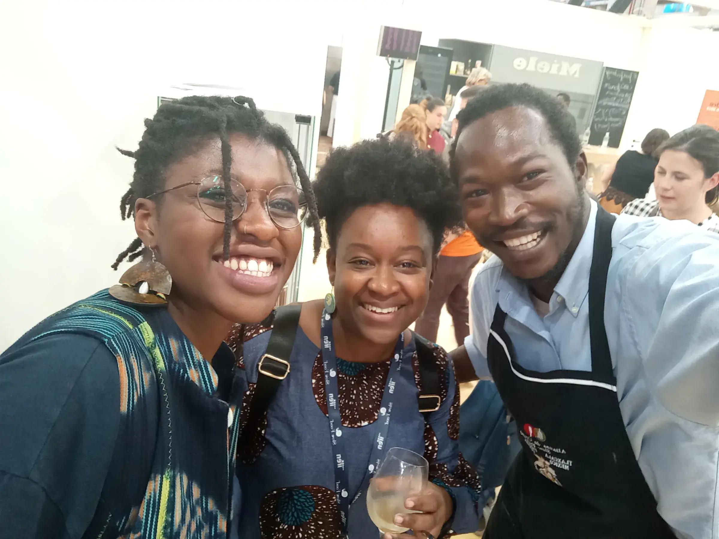 Trois jeunes gens sourient en tenant des verres.