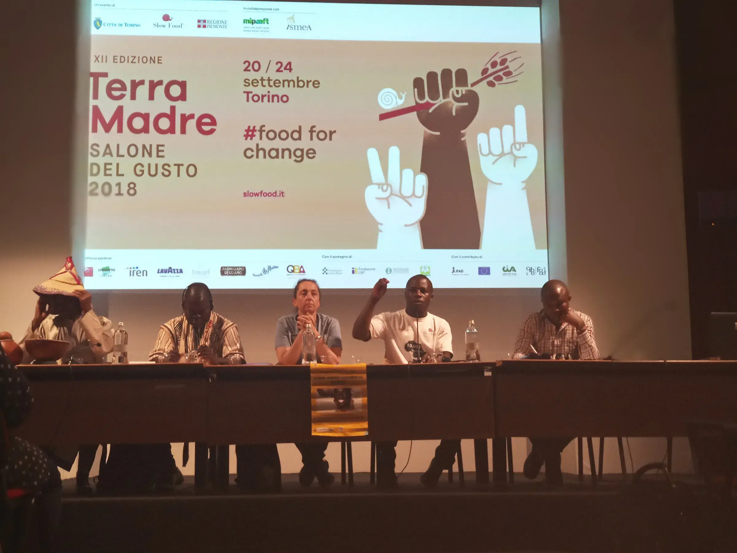 Une table ronde sur scène sous l’écran « Terra Madre #FoodForChange ».