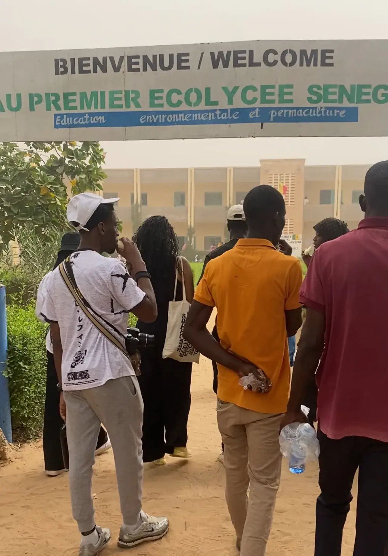 Des jeunes entrent dans l’enceinte du premier Écolycée du Sénégal, sous un panneau de bienvenue
