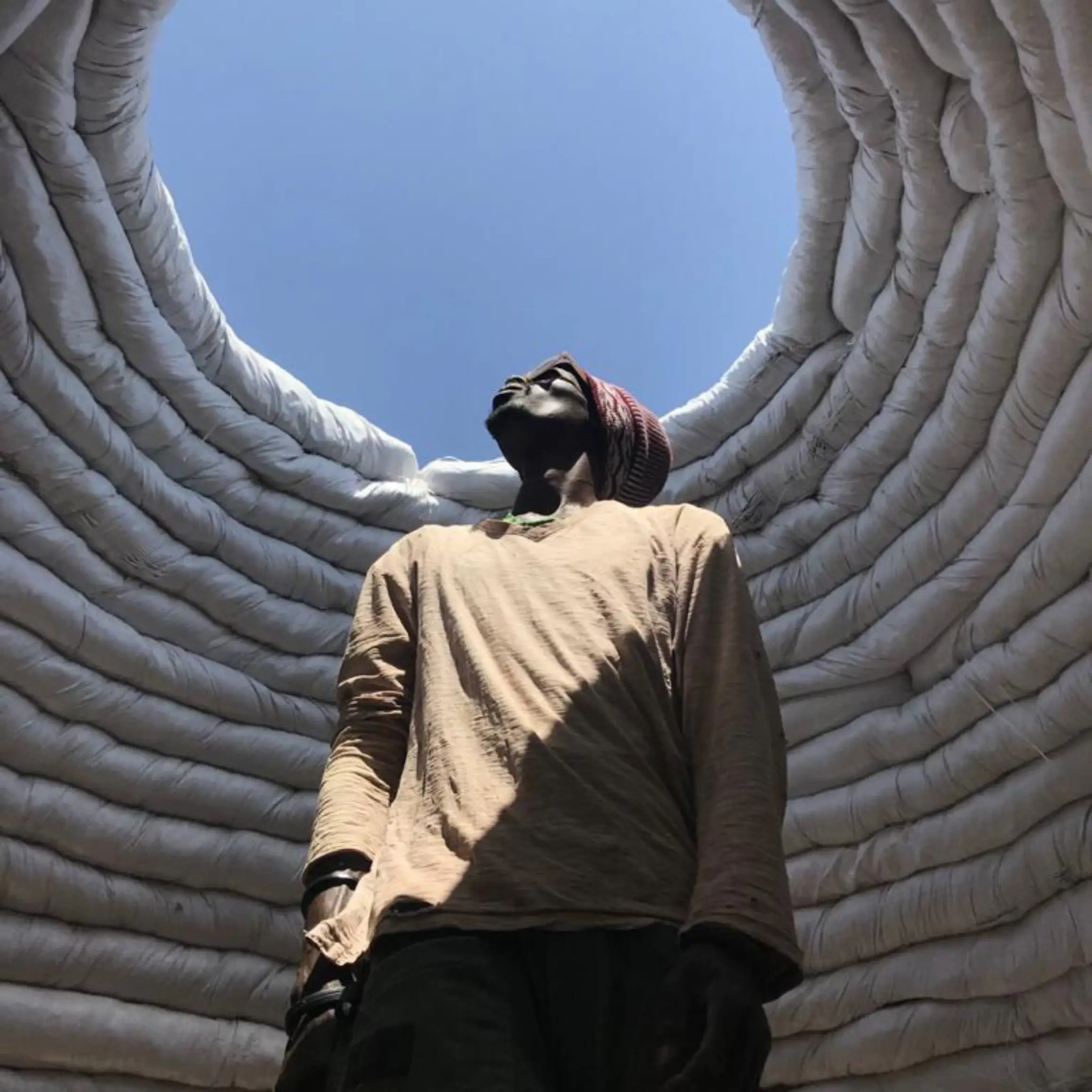 Une femme vue de dos sous une structure ajourée qui découpe le ciel.