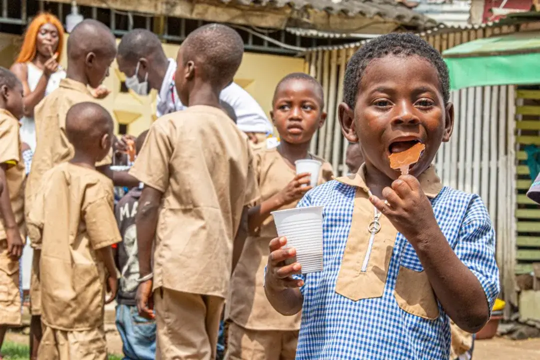 Des enfants sourient en dégustant des tablettes de chocolat.