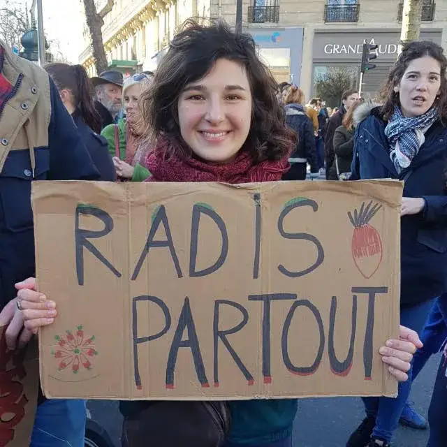 Une manifestante tient une pancarte « Radis partout » lors d’une mobilisation