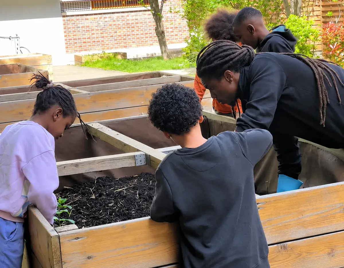 Des jeunes préparent des bacs de culture dans un jardin partagé