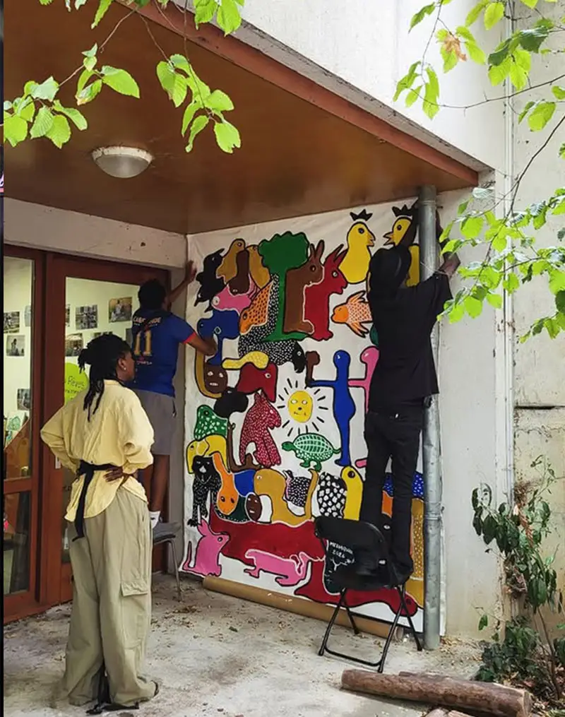 Pose d’une fresque collective colorée sur un mur du quartier