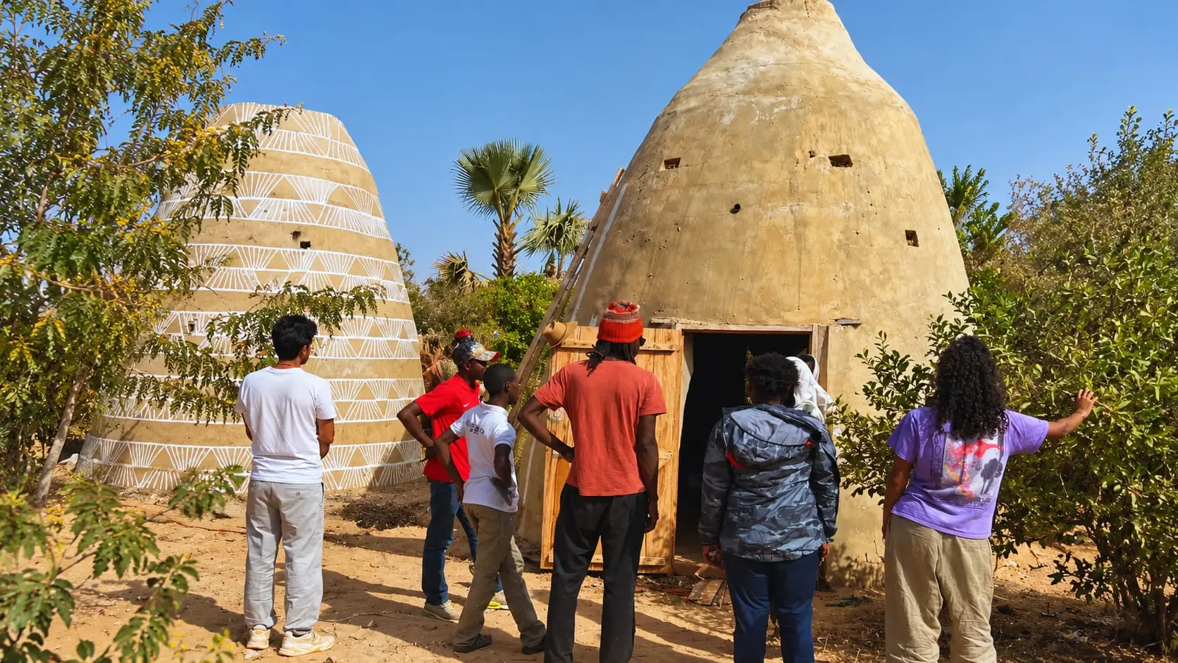 Participants réunis devant des constructions en terre lors d’une immersion JokkoTours Engagé